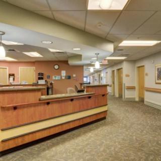 A hospital reception area with a wooden desk and overhead lighting.