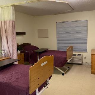 A clean and organized hospital patient room with two beds and essential furniture.
