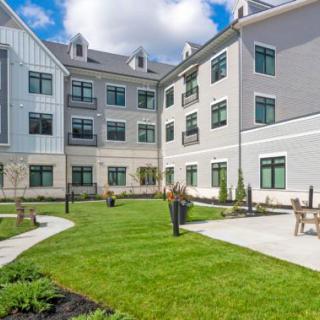 A modern residential building with a landscaped courtyard featuring green lawns and walkways.