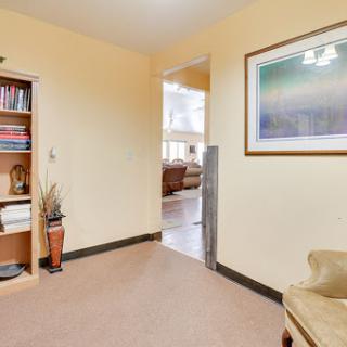 A cozy interior hallway featuring a bookshelf and framed artwork, leading to a living area.