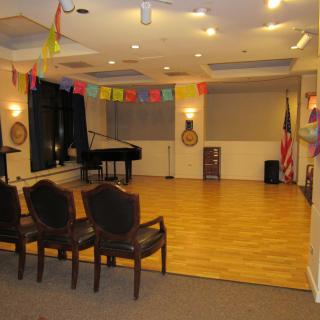 An event space featuring a piano, chairs, and colorful decorations.