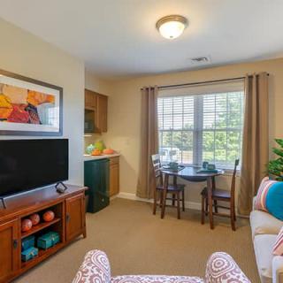 A cozy living room with a television, sofa, and a dining area by the window.