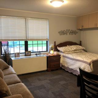 A cozy bedroom with a bed, sofa, and window.