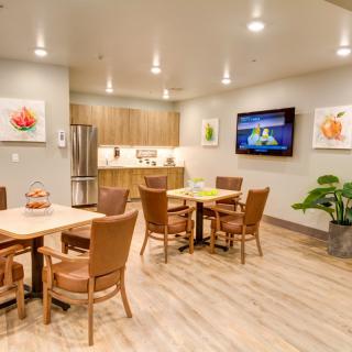 A modern dining area with wooden furniture and a small kitchen.