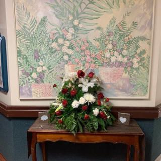 A floral arrangement on a wooden table beneath a colorful painting.