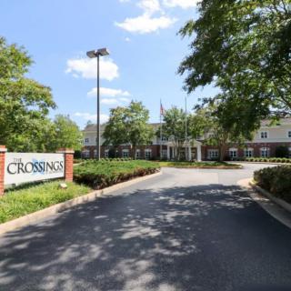 Entrance to a building with a sign and landscaped driveway.