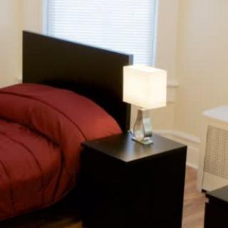 A cozy bedroom with a dark headboard bed and a nightstand featuring a modern lamp.