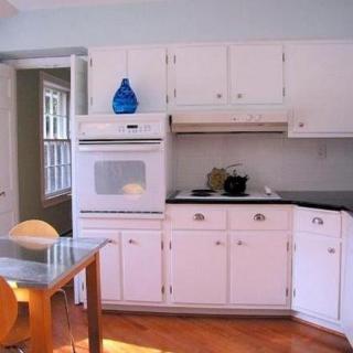 A modern kitchen with white cabinets and a wooden dining table.