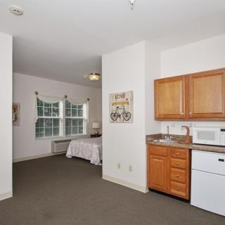 A cozy studio apartment featuring a kitchenette and a sleeping area.