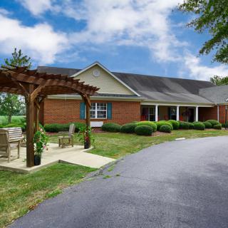 A scenic view of a building with a pergola and surrounding greenery under a blue sky.