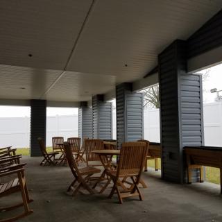 A covered outdoor patio area with wooden tables and chairs.