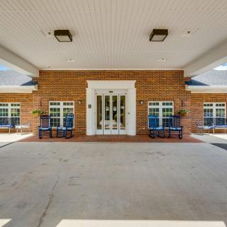 The image shows the entrance of a brick building with a covered walkway and benches on either side.