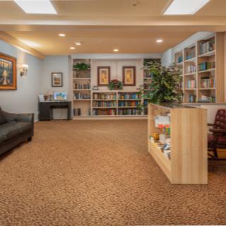 A cozy library room with bookshelves, seating, and decorative elements.