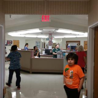 A child stands in the hallway of a busy hospital reception area.