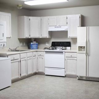 A clean and simple kitchen with white cabinets and standard appliances.