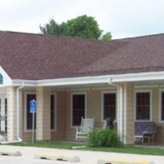 A suburban residential building with a porch and a sloped roof.