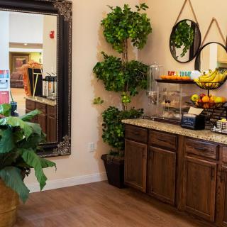 A cozy kitchen corner with a large mirror, plants, and a fruit-laden counter.
