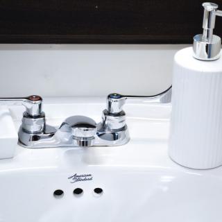 A clean bathroom sink with a chrome faucet and a white soap dispenser.