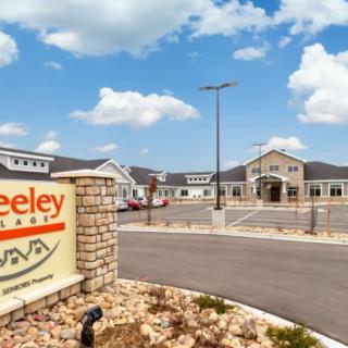 Entrance to a residential facility with clear skies and a well-maintained parking area.