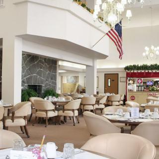 A well-lit dining area with neatly arranged tables and chairs, featuring an American flag and elegant decor.
