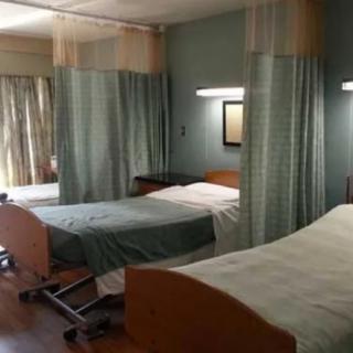 A hospital room with multiple beds and privacy curtains.