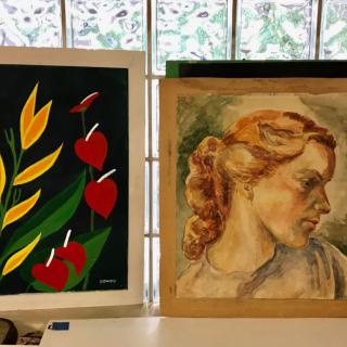 A display of two paintings featuring a floral design and a portrait.
