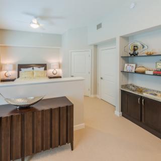 A modern bedroom with stylish decor featuring a bed, lamps, and shelving.