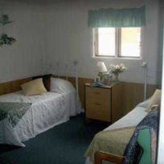 A modest bedroom with two single beds, a nightstand, and a window.