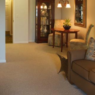 A cozy living room featuring a sofa, armchair, and a small table with lighting.