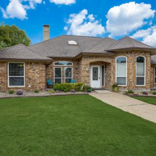 A brick house with a well-maintained lawn and a clear blue sky.