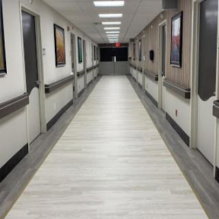 A well-lit corridor in a hospital, featuring white walls and modern flooring.
