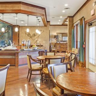 A cozy dining area with wooden tables and chairs, featuring elegant lighting fixtures.