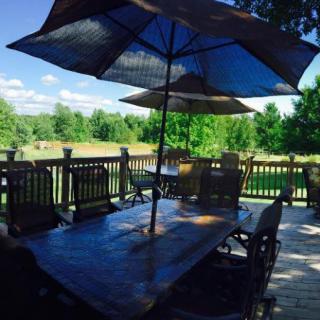 A scenic outdoor patio with a table, chairs, and large umbrellas overlooking lush greenery.