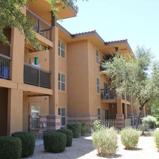 Exterior view of a residential apartment building with surrounding trees and bushes.