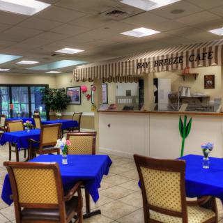 An empty restaurant with blue tablecloths and neatly arranged tables and chairs.