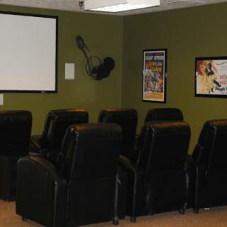 A cozy home theater setup with recliner seating and a projector screen.