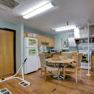 A kitchen and dining area with appliances and a round table surrounded by chairs.