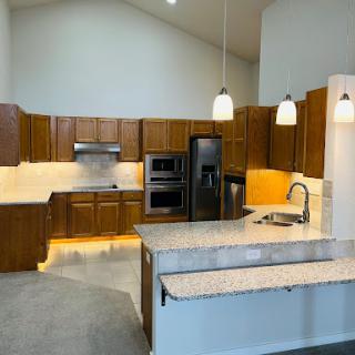 A modern kitchen featuring wood cabinetry, granite countertops, and bright lighting for an inviting cooking space.
