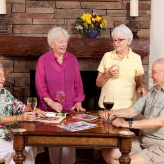 A group of seniors enjoying each other's company with drinks around a table.