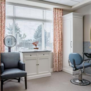 A bright and modern salon interior with chairs and a mirror by the window.