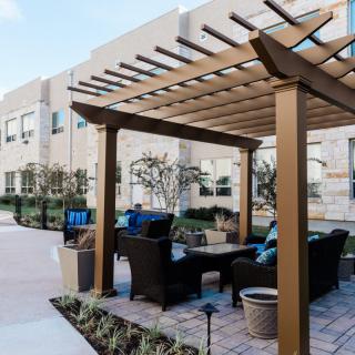 An inviting outdoor seating area featuring a wooden pergola, comfortable furniture, and modern landscaping.