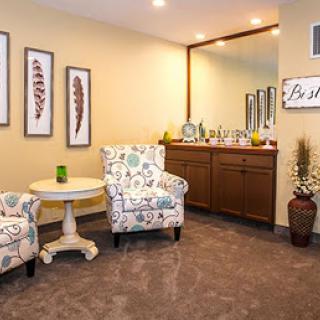 A cozy corner featuring two floral chairs, a small table, and decorative artwork on the walls.