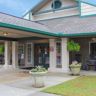 A welcoming building entrance with a porch and decorative plants.