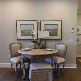 A cozy dining area with a round table, four chairs, and decorative artwork on the walls.