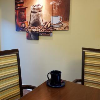 A cozy kitchen setup with a coffee-themed artwork, a table, and chairs.