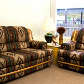 A cozy living room featuring patterned sofas and a small table with a lamp.