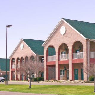 A two-story commercial building with a brick exterior and green roof under a clear sky.