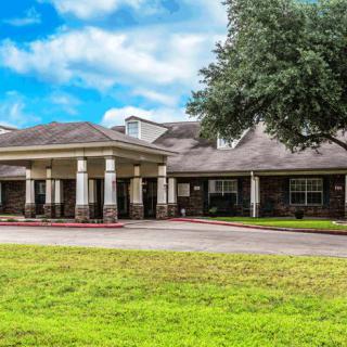 A residential building with a grassy lawn and a cloudy sky.