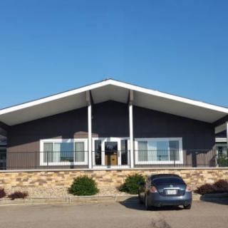 A building with a distinctive roof design, featuring a car parked in front within a parking lot on a clear day.