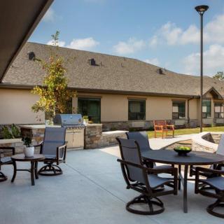 A sunny outdoor patio with tables and chairs in front of a building.